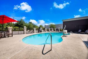 a swimming pool with a red umbrella and a table at Comfort Suites Northlake in Charlotte