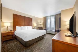 a hotel room with a bed and a flat screen tv at Comfort Inn & Suites Orem - Provo in Orem