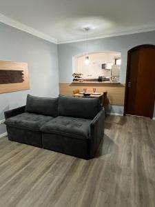 a living room with a black couch and a kitchen at FLAT no Gonzaga com estacionamento incluso in Santos