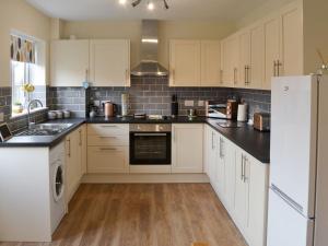 a kitchen with white cabinets and black counter tops at Sandy Toes in Mundesley