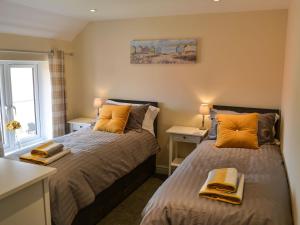 two beds in a small room with two lamps at Sandy Toes in Mundesley