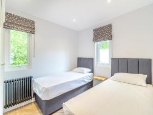 two beds in a room with two windows at Greenacres Cabin in Coleford