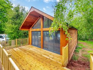 a house with a wooden deck with glass doors at Greenacres Cabin in Coleford