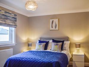 um quarto com uma cama com lençóis azuis e uma janela em Teithbank em Callander