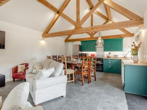 a kitchen and living room with green cabinets and a table at The Maltings - Uk44460 in Kingscote