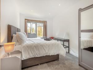 a white bedroom with a bed and a window at The Maltings - Uk44460 in Kingscote