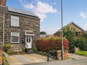 a brick house with a solar roof on it at Red Robin Cottage in Wingerworth