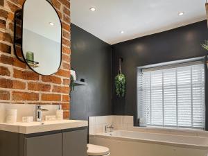 a bathroom with a brick wall and a sink and a tub at Red Robin Cottage in Wingerworth