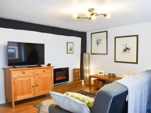 ein Wohnzimmer mit einem Sofa und einem TV in der Unterkunft The Old Buttery in Chulmleigh