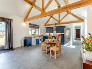 a kitchen with blue cabinets and a table and chairs at The Granary - Uk44454 in Kingscote