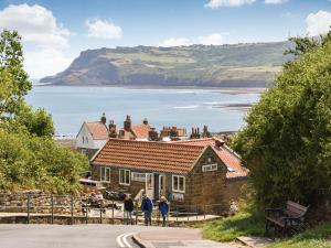 pessoas em pé em frente a uma casa com vista para o oceano em Glenhowen em Robin Hood's Bay