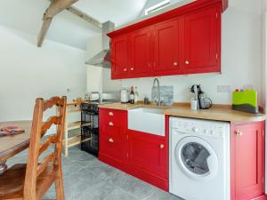 a kitchen with red cabinets and a washing machine at The Stables - Uk44477 in Kingscote