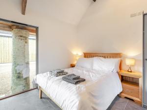 a bedroom with a white bed and a large window at The Stables - Uk44477 in Kingscote