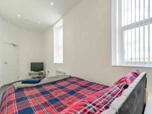 a bedroom with a bed with a plaid blanket at Number Four - Uk44899 in Brierfield