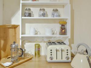 a kitchen counter with a toaster and other items on shelves at Garden Cottage in Rottingdean