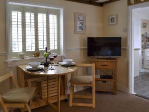 a dining room with a table and a television at Garden Cottage in Rottingdean