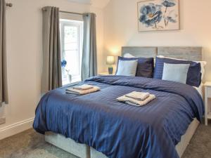 a bedroom with a blue bed with towels on it at Salty Kisses in Mundesley