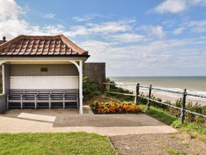 a building with a bench next to the beach at Salty Kisses in Mundesley