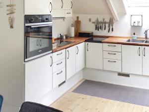 eine Küche mit weißen Schränken und einer Spüle in der Unterkunft Bright Cottage with Hot Tub - By Traum Ferienwohnungen in Ebeltoft + 30 Fotos