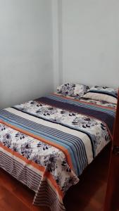 a bed with a blanket and pillows on it at Alojamiento Same in Volcán Chimborazo