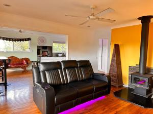 sala de estar con sofá de cuero y estufa de leña en Mountain View, en Woombye