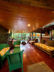una sala de estar con muebles verdes y techo de madera. en Colores de la Sierra en Minca