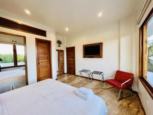a bedroom with a bed and a tv and a chair at Lava Heron Galapagos Apartment in Puerto Ayora +1 photo