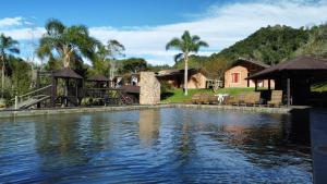 a house with a swimming pool next to a body of water at Pousada das Hortênsias in São Bonifácio