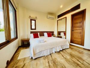 a bedroom with a large white bed with red pillows at Lava Heron Galapagos Apartment in Puerto Ayora