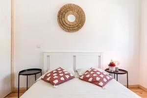 a bed with two pillows and a mirror on the wall at Bento Guest House in Porto