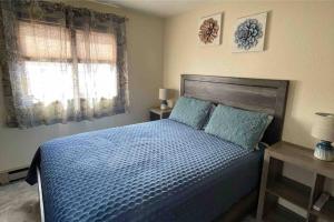 a bedroom with a bed with blue sheets and a window at Parkway Yellowstone Guest House Apartment #5 in Gardiner