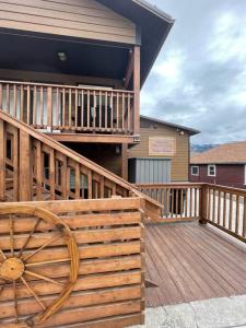 una terraza de madera con una rueda de madera en una casa en Parkway Yellowstone Guest House Apartment #5 en Gardiner
