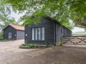 a black house with a fence next to it at The Stables in Cheriton