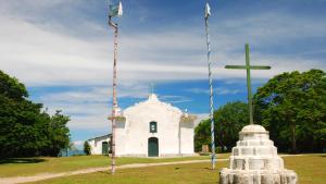 een kleine witte kerk met een kruis en een paal bij Manoah Trancoso in Trancoso