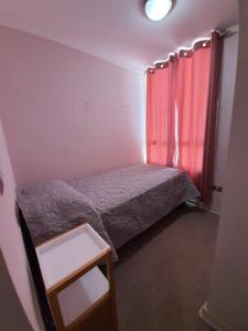a small bedroom with a bed and a red curtain at Depto. Condominio La Herradura, Coquimbo in Coquimbo