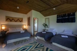 a bedroom with two beds and a wooden ceiling at Colores de la Sierra in Minca