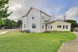 a white house on a grassy yard in front of a house at Cozy Starkville Apartment Walk to Main Street! in Starkville