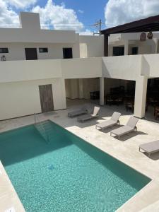 a swimming pool with chairs and a house at Nuxká Hotel by Heaven in Telchac Puerto