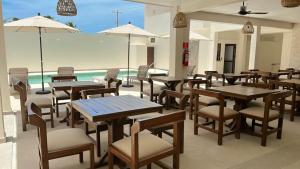un restaurante con mesas y sillas y una piscina en Nuxká Hotel by Heaven en Telchac Puerto