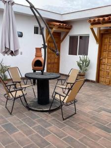 un patio con mesa, sillas y sombrilla en Bella Vizcaína 6 recámaras con baño privado. en Mineral de Pozos