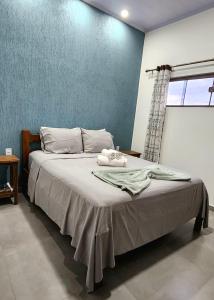 uma cama num quarto com uma parede azul em Casa Ypê - Vila de São Jorge em Alto Paraíso de Goiás