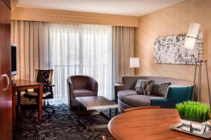 Courtyard by Marriott Kansas City Shawnee في شاوني: غرفة معيشة مع أريكة وكراسي في غرفة في الفندق