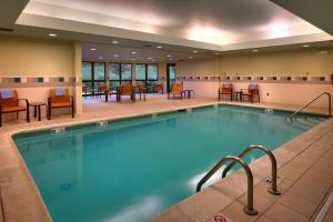 a pool in a hotel room with chairs and tables at Courtyard by Marriott Kansas City Shawnee in Shawnee