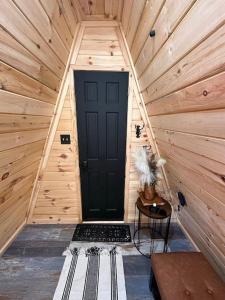 a wooden cabin with a black door in a room at Acres Away in Penn Yan