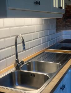 un fregadero de acero inoxidable en una cocina con armarios azules en Gotell, en Erikslund