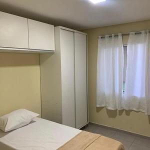 加拉尼溫斯的住宿－CASA COM PISCINA GARANHUNS，卧室配有白色的床和窗户。