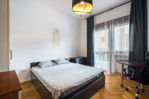 een slaapkamer met een bed, een bureau en een raam bij Sleek Comfort - A Blend of Style and Convenience in Boekarest