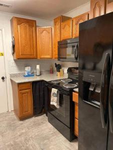 una cocina con electrodomésticos negros y armarios de madera en Comfort & Quiet in a central location, en Elizabeth City