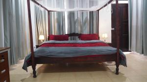 1 dormitorio con cama con dosel y almohadas rojas en Siswi (The Nest)- The place to be., en Bungoma
