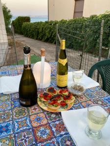 a table with two bottles of wine and a plate of food at Casa Frontemare in Carloforte